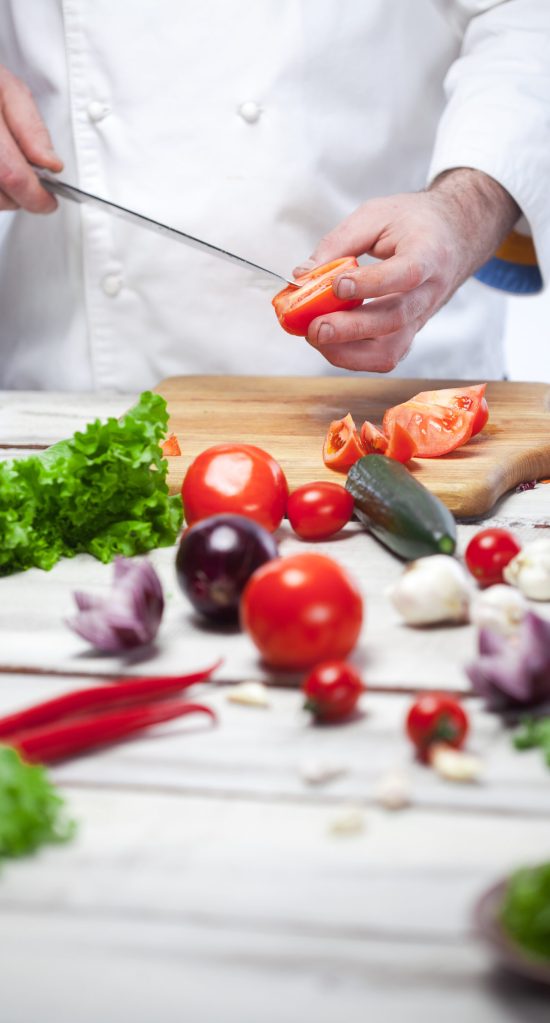 The hands of chef cutting a red tomato in his kitchen on white background with Empty blank for the recipe