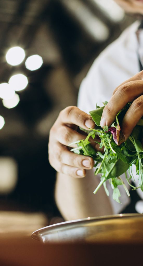 Chef at the kitchen preparing salad